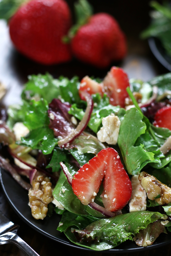 Up close photo of a plate of Spring Mix Salad with strawberries and walnuts.