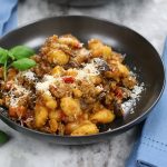 A serving of Goulash with Italian Sausage that is garnished with grated parmesan and basil leaves.