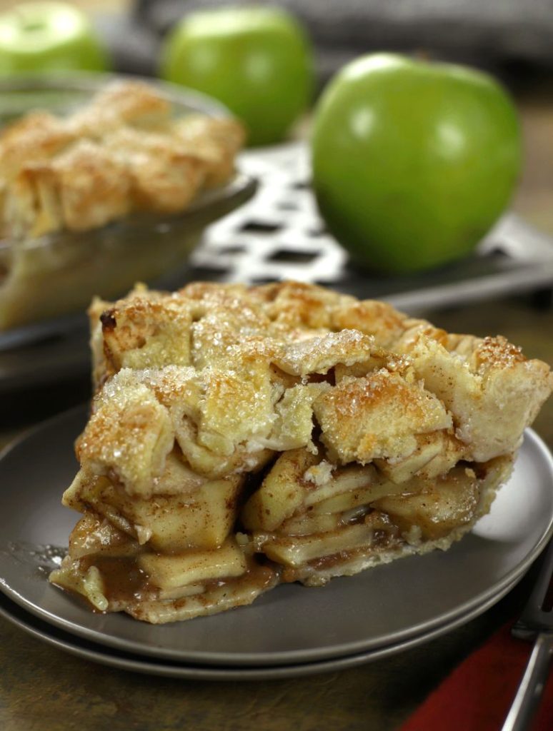 A slice of Homemade Apple Pie served on a small brown plate.