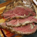 Bone-in prime rib roast sliced to reveal a perfectly rare interior and a beautifully seared crust.