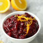 Up close photo of Cranberry Orange Sauce in a white bowl and garnished with orange zest strips.