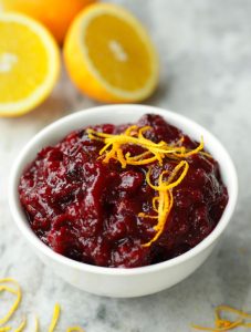 Up close photo of Cranberry Orange Sauce in a white bowl and garnished with orange zest strips.