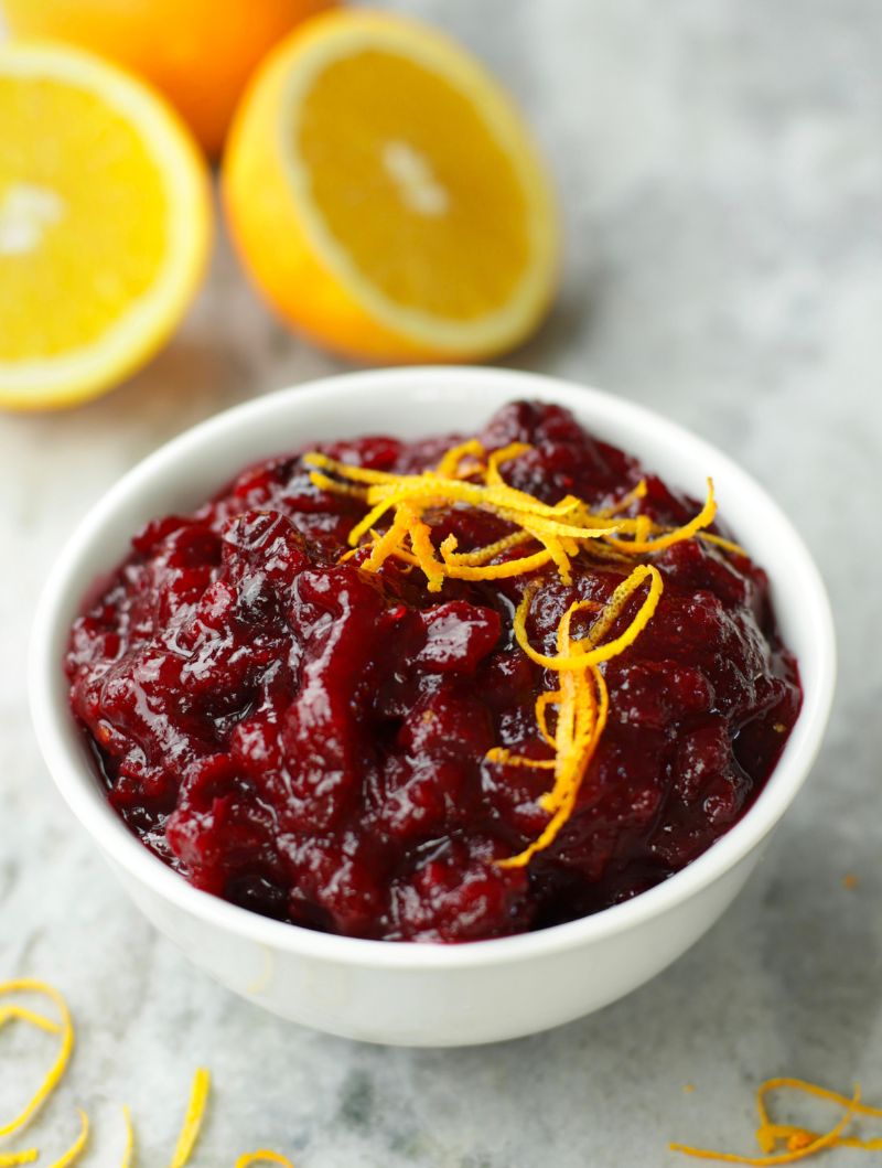 Up close photo of Cranberry Orange Sauce in a white bowl and garnished with orange zest strips.